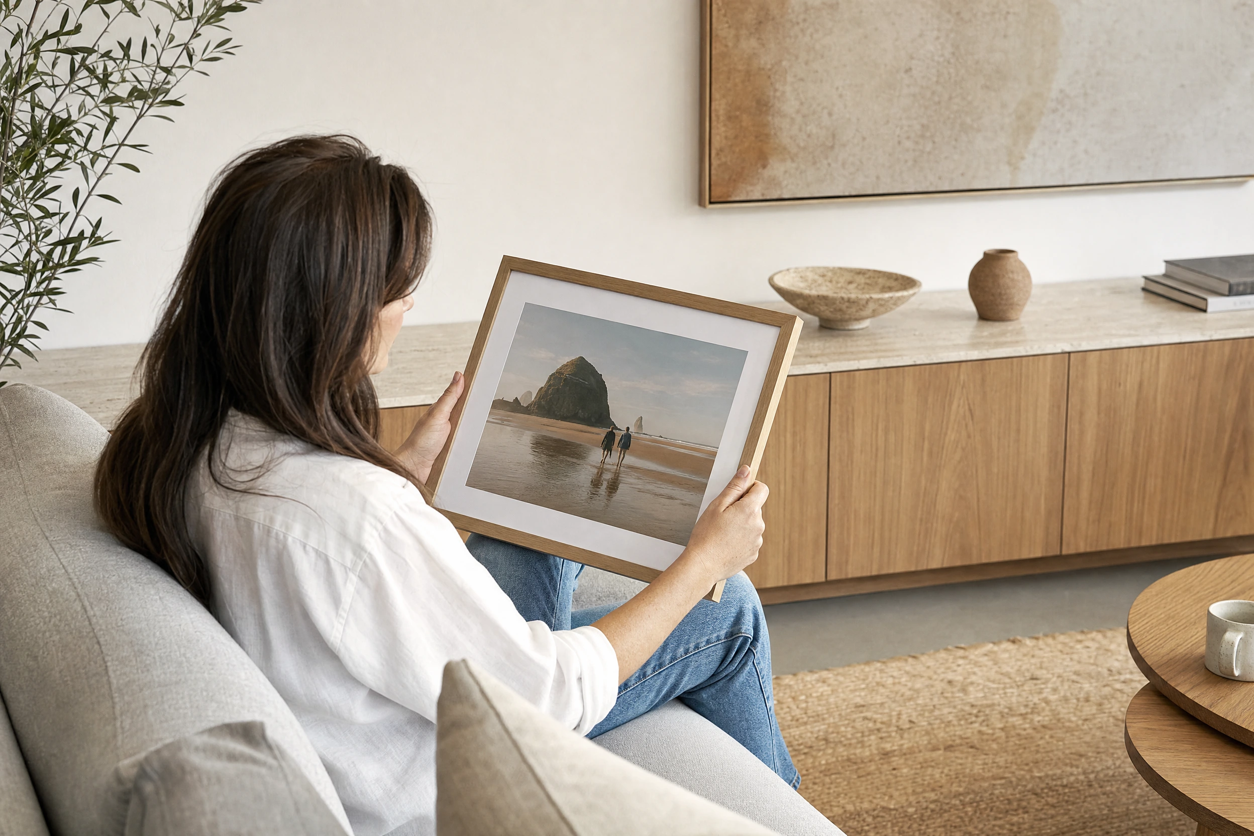 AI illustration of a woman looking at a framed beach photograph in a living room.